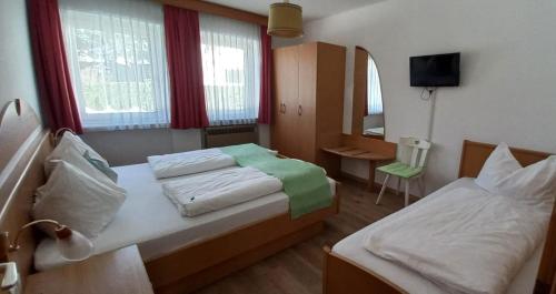 a hotel room with two beds and a television at Residence die Färbe in Vipiteno