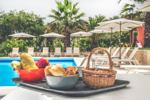 ein Tablett mit Brot und Körben auf einem Tisch in der Nähe eines Pools in der Unterkunft The Palm Garden in Ermones