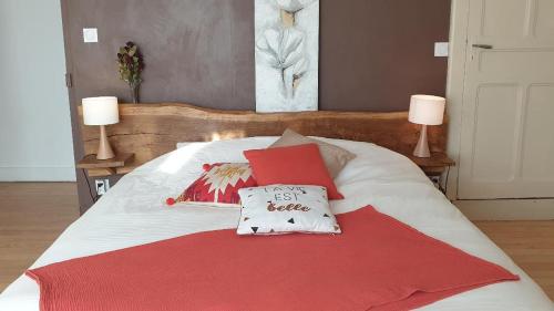 a bed with two pillows and a red blanket at Chambre calme Aux Iris in Grandvelle-et-Perrenot