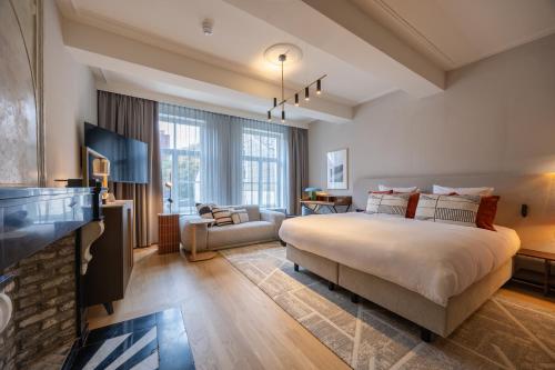 a bedroom with a large bed and a living room at Hotel Maison Maastricht Centrum - Handwritten Collection in Maastricht