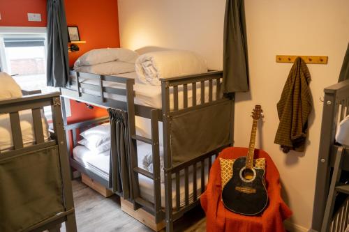 a room with three bunk beds and a guitar at Railway Sleeper Hostel in Castlerock