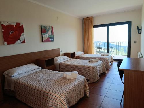 a hotel room with three beds and a balcony at Cor De Prades in Mont-ral