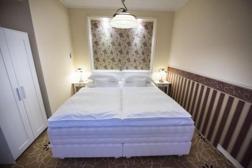 a bedroom with a large white bed with two lamps at Golden Royal Boutique Hotel & Spa in Košice