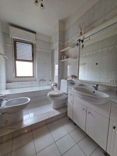 a bathroom with two sinks and a tub and a toilet at Appartamento Polidea in Reggio di Calabria