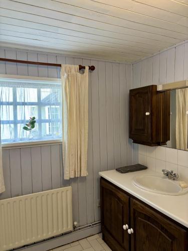 a bathroom with a sink and a mirror and a tub at Bay View Ridge Cottage in Bantry