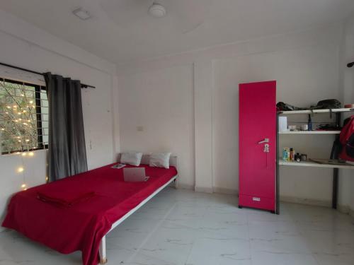 a bedroom with a red bed and a pink door at The Long Stay Goa in Arambol