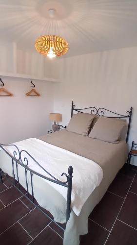 a bedroom with a white bed with a chandelier at Mini-maison indépendante vue montagne- Corse in Poggio-Marinaccio