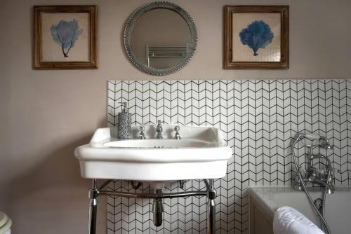 a bathroom with a white sink and a mirror at The Gatehouse in Peterborough