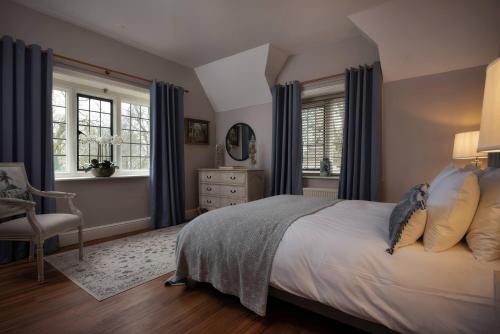 a bedroom with a bed with blue curtains and a chair at The Gatehouse in Peterborough