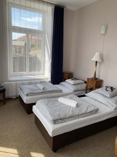 three beds in a room with a window at Hotel Koruna penzion in Teplice nad Metují