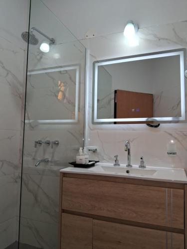 a bathroom with a sink and a shower with a mirror at CASABLANCA CATAMARCA Guest House in San Fernando del Valle de Catamarca