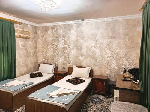two beds in a room with green curtains at Hotel Nazira & Azizbek in Bukhara