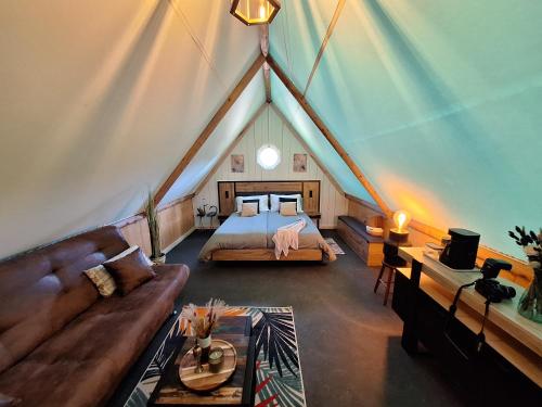 a bedroom in a tent with a bed and a couch at La Découverte Trouvée in Auxon