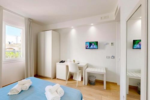 a bedroom with a bed and a desk and a table at Hotel Perla Gaia in San Vito lo Capo
