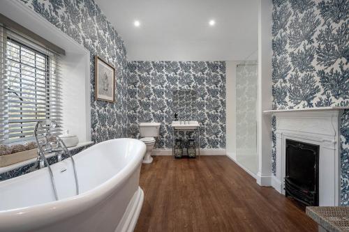 a bathroom with a white tub and a fireplace at Greenwood Manor in Peterborough