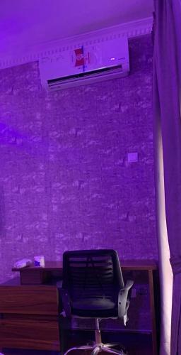 a purple room with a chair in front of a wall at Kris Courts in Ibadan