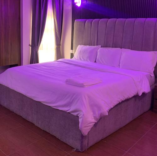 a large bed with purple sheets and pillows at Kris Courts in Ibadan