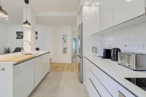 a white kitchen with white cabinets and a sink at Fonte Nova Nest, By Home Match in Setúbal