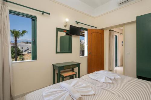 two beds in a bedroom with a table and a window at Gianna Apartments in Almyrida