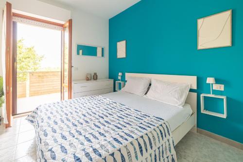 a blue bedroom with a bed and a large window at Fiordaliso in Alba Adriatica