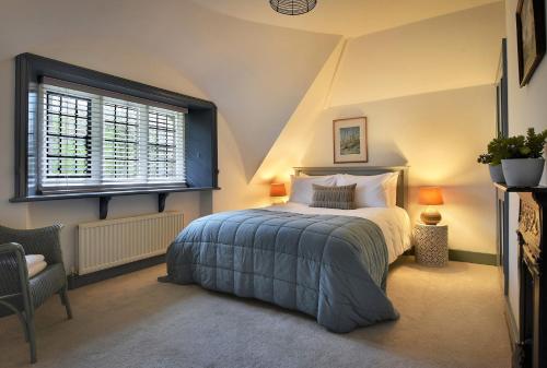 a bedroom with a bed and a chair and a window at Home Farm Cottage in Peterborough