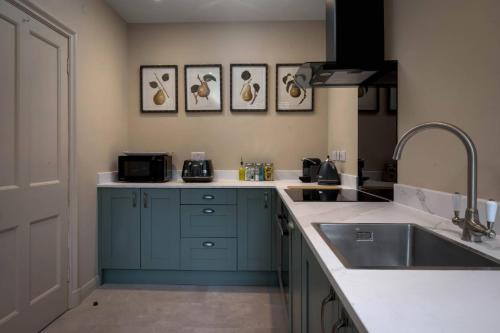 a kitchen with blue cabinets and a sink at Rubens Rooms in Peterborough