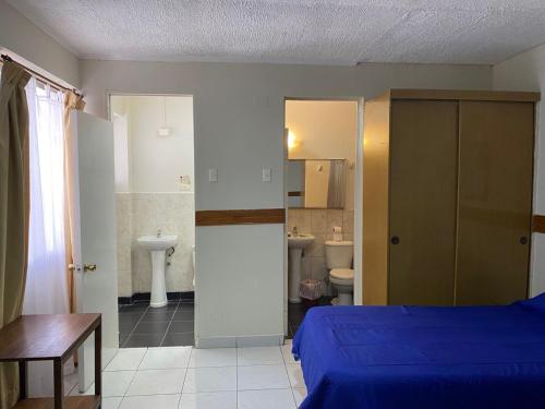 ein Schlafzimmer mit einem blauen Bett und ein Badezimmer in der Unterkunft HOTEL ASTORE Matta 2537 in Antofagasta