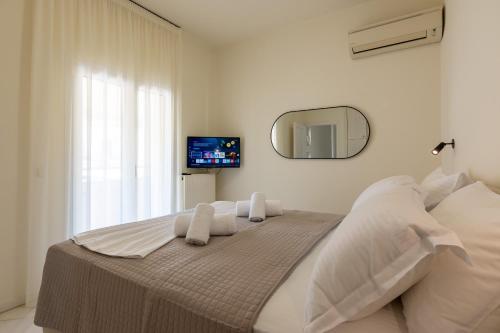a white bedroom with a large bed with a mirror at MAREL Luxury Residence Malia in Malia