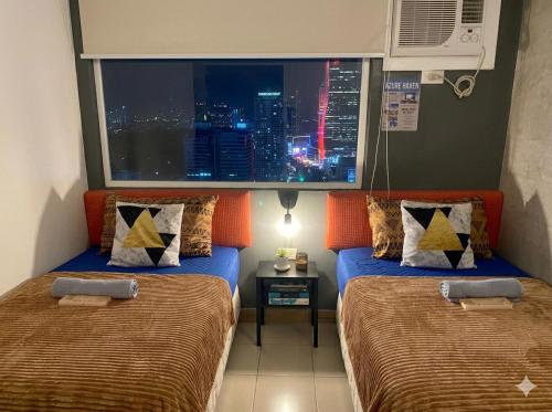 two beds in a room with a view of a city at Isaiah CityScape in Manila