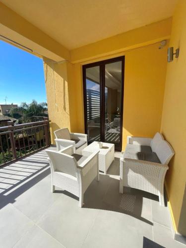 a patio with wicker chairs and tables on a balcony at Deluxe Appartment in Cinisi