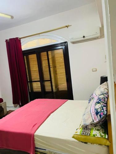 a bedroom with a bed with a red and white blanket at Chatet on Casabinca NorthCoast in Dawwār Abū Maḩrūs