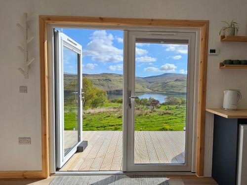 an open door with a view of a lake at Croft Seven Cabins in Port na Long