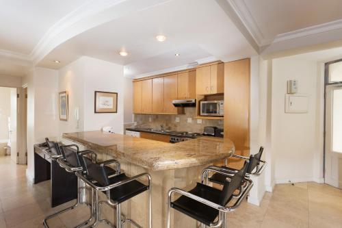 a kitchen with a large counter with chairs around it at The Stellenbosch Hotel in Stellenbosch