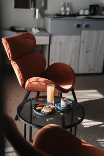 a coffee table with two chairs and a glass of orange juice at Hotel Cristal Park in Tarnów