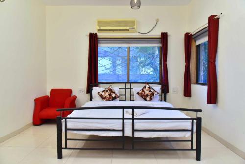 a bedroom with a bed and a red chair at Sheth lov villa in Lonavala