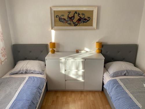 a bedroom with two beds and a dresser between them at Sun Apartment in Tivat