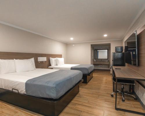 a hotel room with two beds and a desk and a television at Economy Suites Springfield - Extended Stay in Springfield