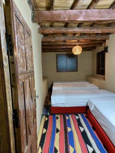 a bedroom with two beds and a door and a rug at Auberge amazrane in Matat