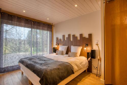 a bedroom with a large bed and a large window at Le Nid du Coderc in Carsac-Aillac