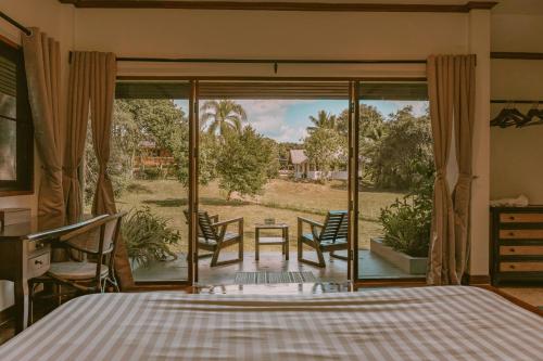 a bedroom with a bed and a view of a yard at The Hideaway Village in Ban Mae Hi