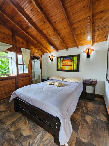 a bedroom with a large bed in a room with wooden ceilings at EcoLodge La Pluma in Salento