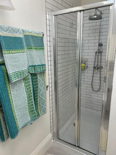 a shower with a glass door with towels on it at Bourne House in Mursley