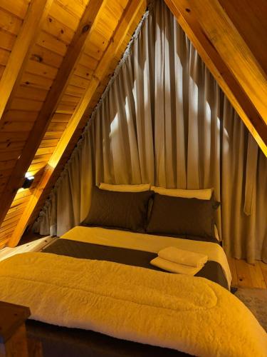 a bed in a room with a wooden ceiling at Chalé Recanto da Ema in Urubici