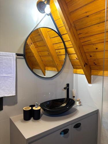 a bathroom with a black sink and a mirror at Chalé Recanto da Ema in Urubici