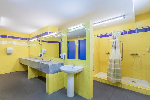 a yellow bathroom with a sink and a shower at HI Beja - Pousada de Juventude in Beja