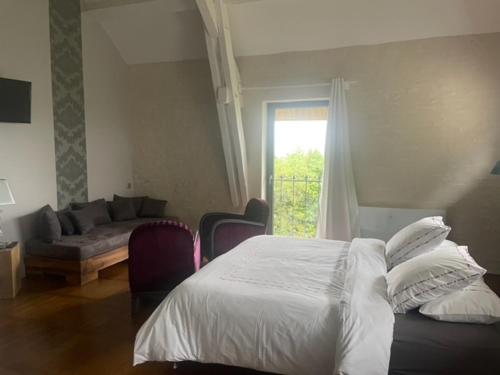 a bedroom with a bed and a couch and a window at chambres d hotes ochene in Daix