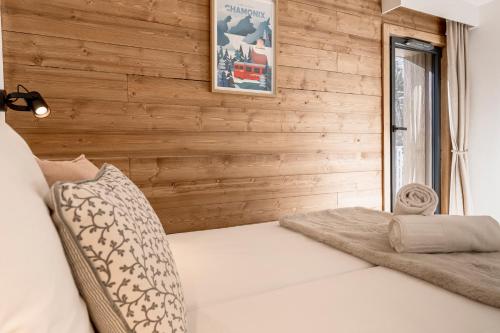 a bed in a room with a wooden wall at Apartment Leo - 2BR, Modern, Lift access, Mountain views in Les Houches