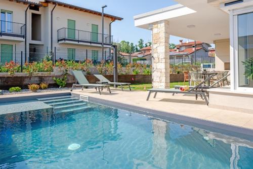 a swimming pool with two chairs next to a house at Villa Milvia in Colà di Lazise