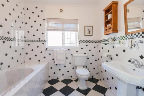 a bathroom with a toilet and a tub and a sink at Medindi Manor in Cape Town