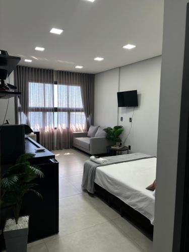 a bedroom with a bed and a couch and a television at Flat Praia da Graciosa in Palmas